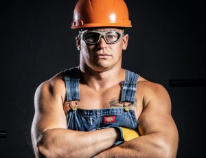 pexels-photo-16552856-16552856 Portrait of a muscular construction worker with arms crossed, wearing goggles and a hard hat.